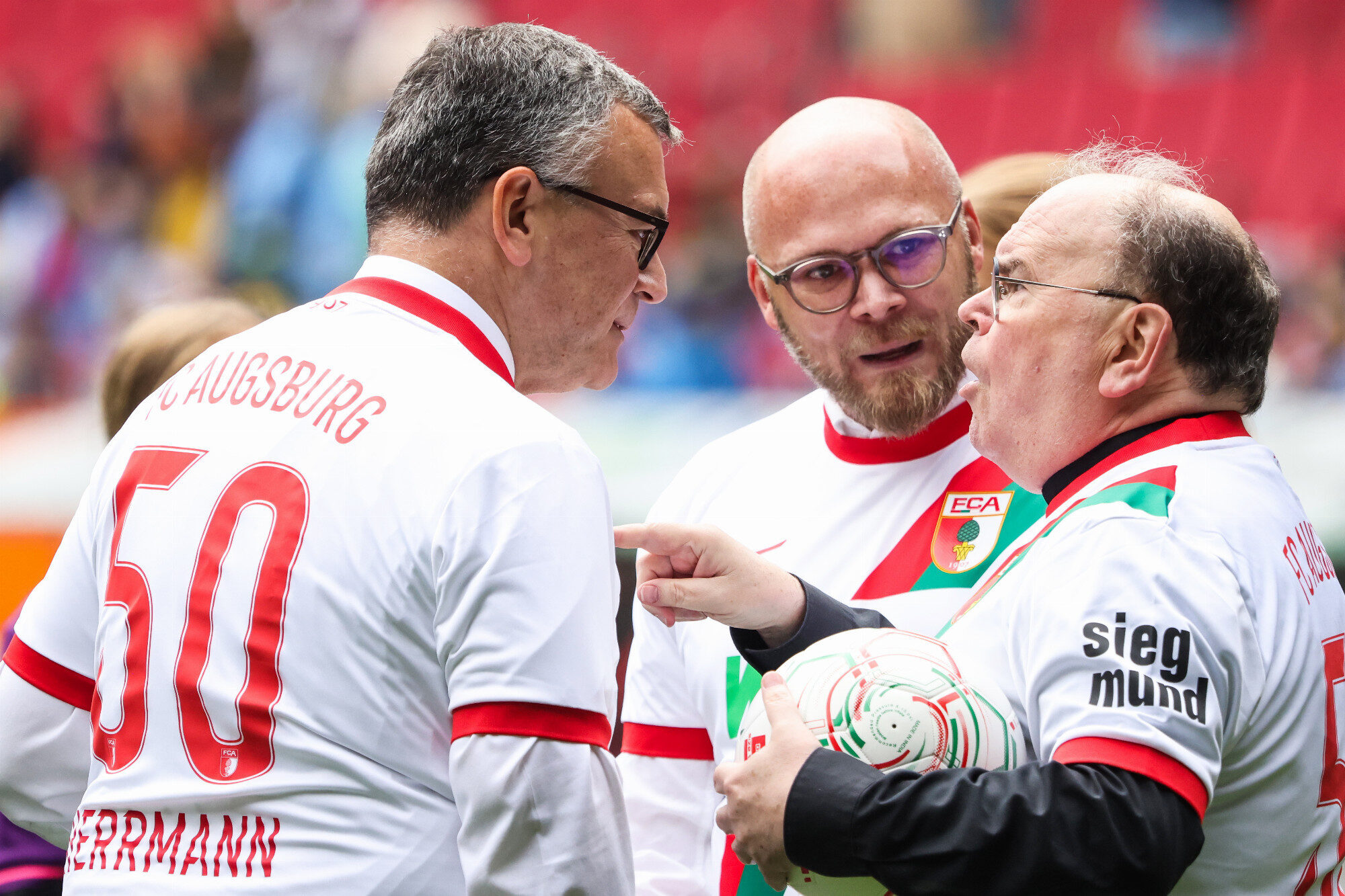 Drei im FCA-Trikot, Bischof Bertram Meier mit Ball unterm Arm, WWK Arena Augsburg / Schulwerk